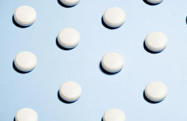 Weiße runde Probiotika Tabletten auf hellblaum Papierhintergrund