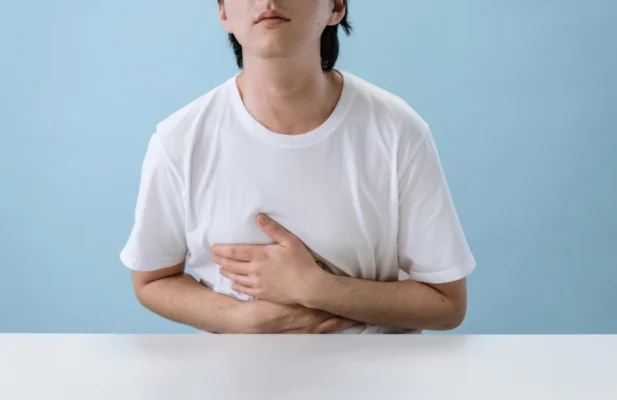 Junger Mann hält sich vor Schmerz den Bauch, weil er Reizdarm und SIBO hat.