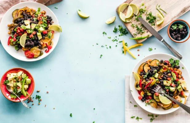 Flatlay Fotografie von Essen auf Tellern, Hintergrund hellblau.