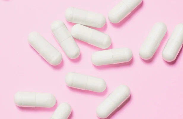 Weiße Tabletten, die auf einem rosa Hintergrund liegen.